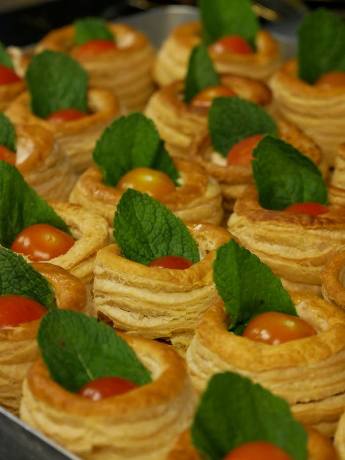 Delicious puff pastries garnished with cherry tomatoes and mint leaves, perfect for gourmet events.