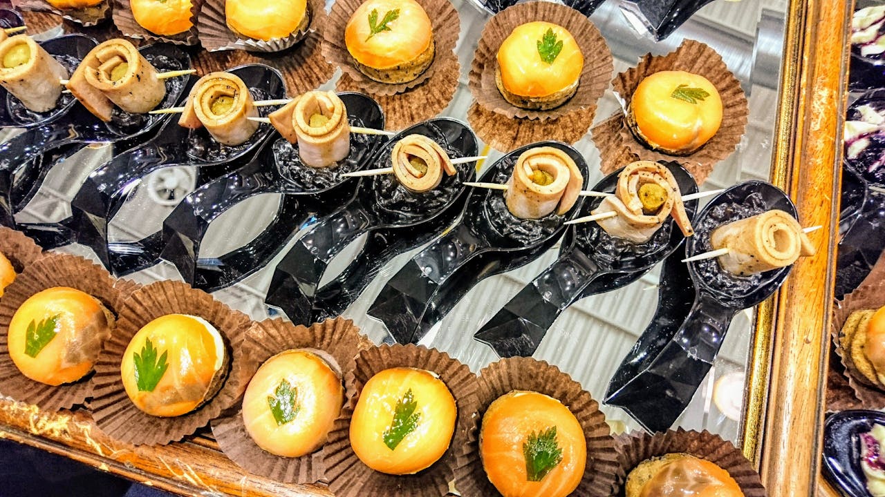 Colorful assortment of gourmet appetizers elegantly presented on a mirrored tray, perfect for events.